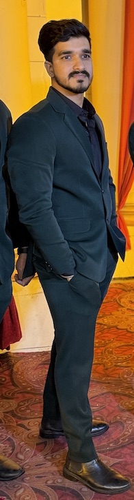 Sonu standing tall in a dark suit, smiling softly